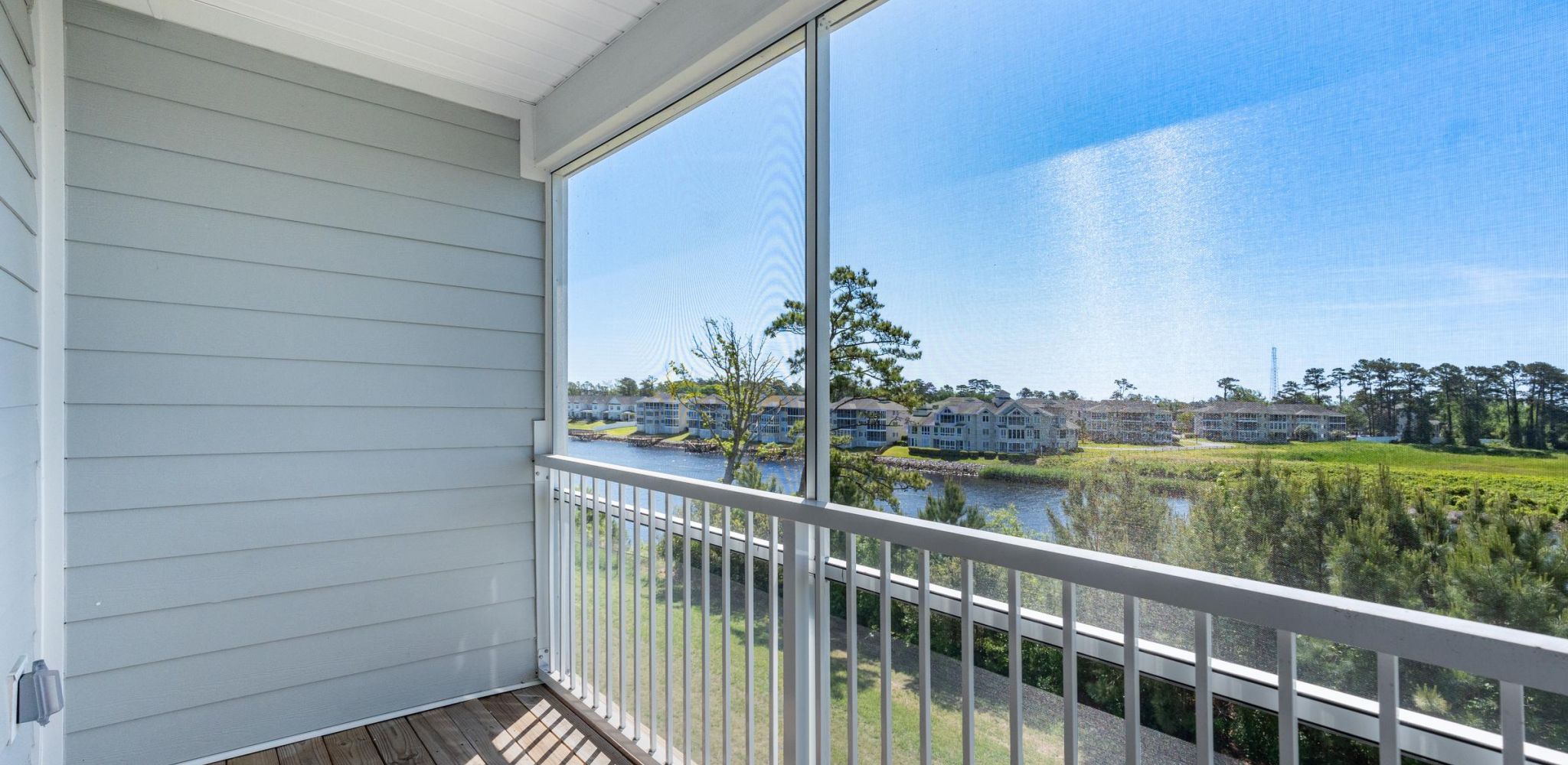 Hawthorne Waterway screened balcony overlooking a serene waterway with distant houses.